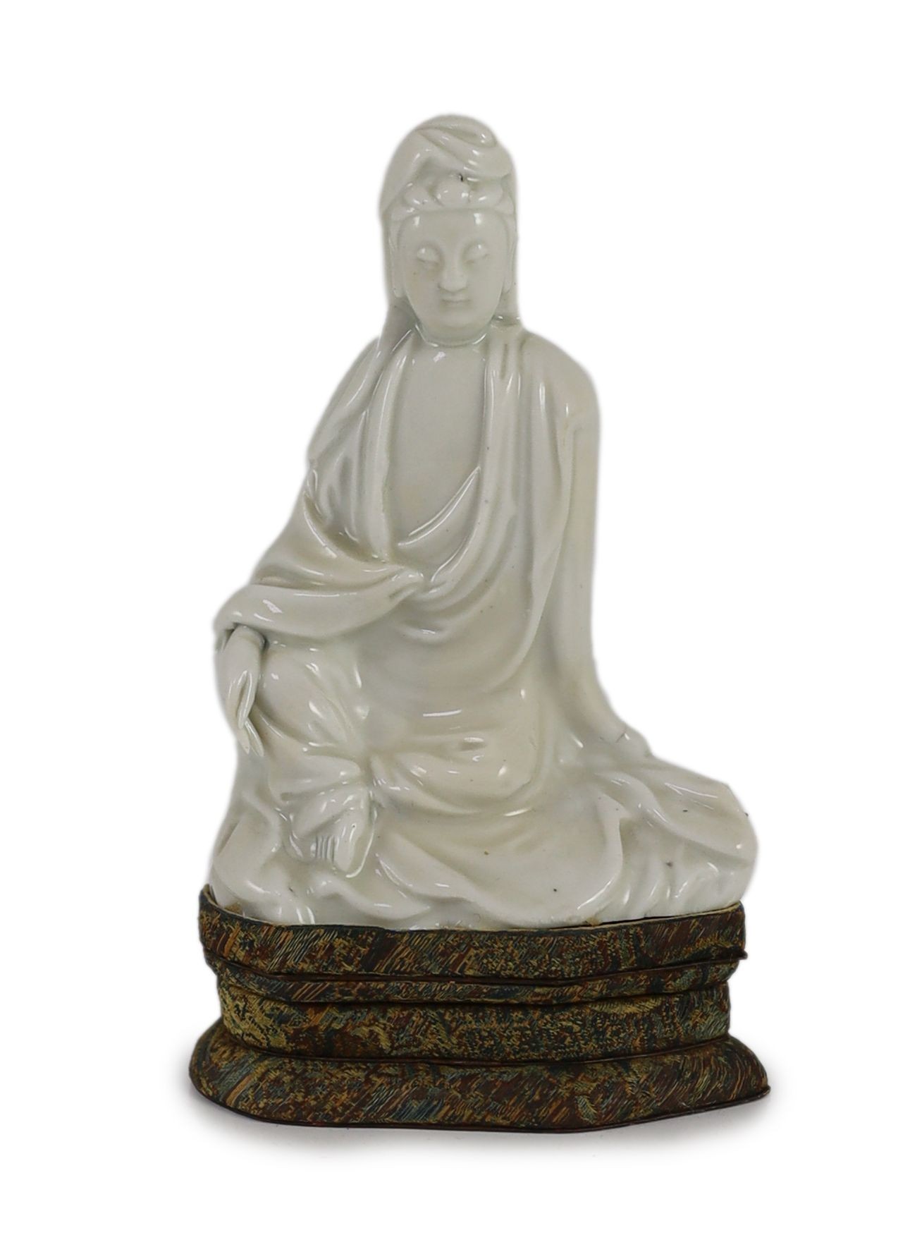 A Chinese blanc-de-chine seated figure of Guanyin, Dehua kilns, 18th century, 12cm high, Brocade covered stand